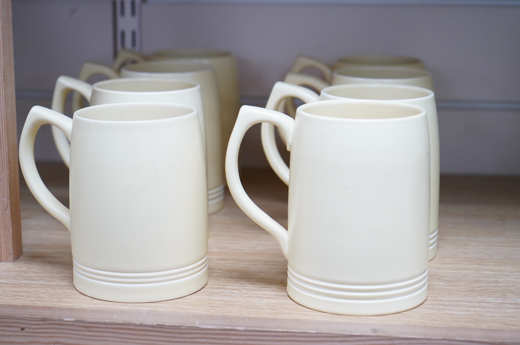 Keith Murray for Wedgwood, a set of eight straw glazed mugs, 12cm high